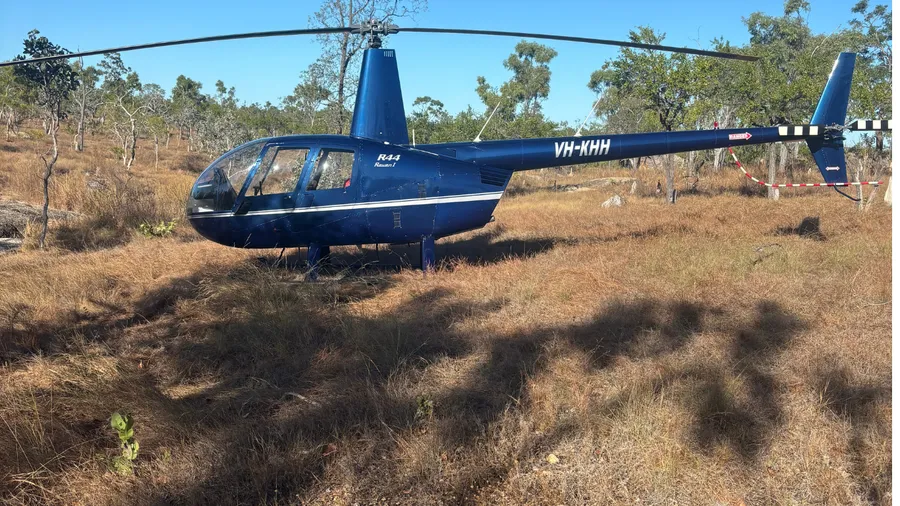 A helicopter parked in open grassland on a remote rural property.