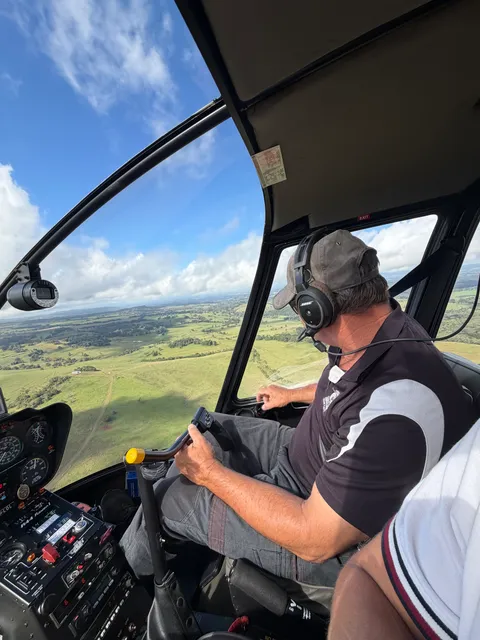 Trevor flying, with green farmland visible through the cockpit.