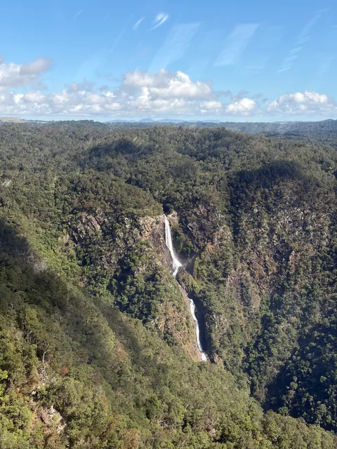 Aerial view of a waterfall cascading down a rainforest gorge in the Tablelands.
