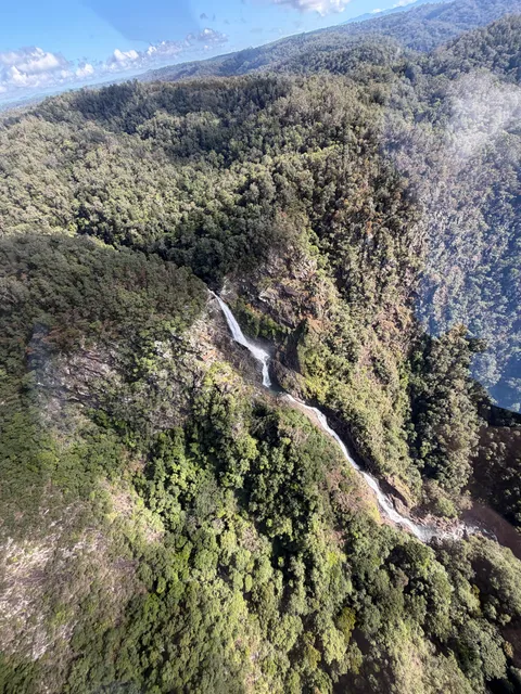 Aerial view of a second waterfall cascading down a forested ridge.