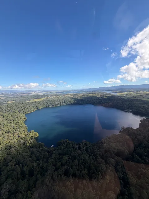 Aerial view of a volcanic crater lake, Lake Barrine, surrounded by rainforest.