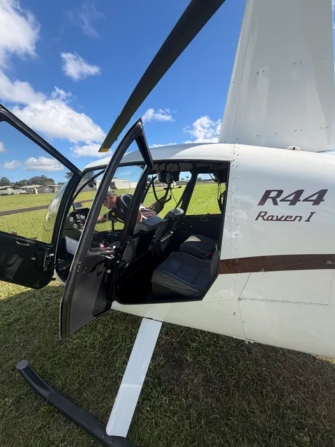 Close-up of the R44 Raven I helicopter's open cabin door, parked on grass.