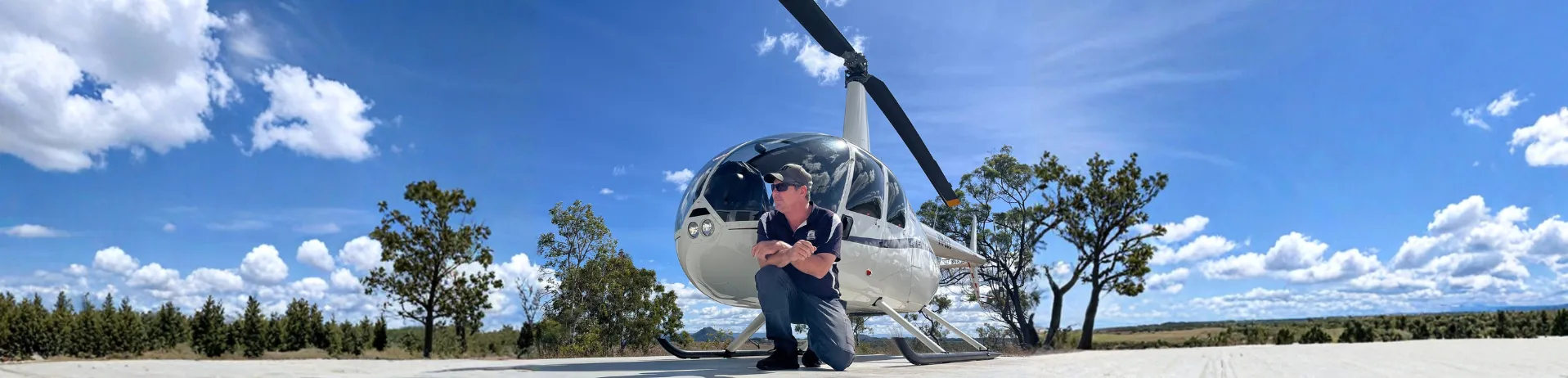 Trevor standing beside an All Terrain Helicopters R44 on a helipad overlooking the Tablelands.