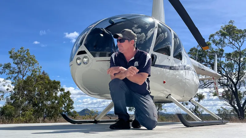 A helicopter parked on a beach near rainforest, Tablelands coastal scenery.
