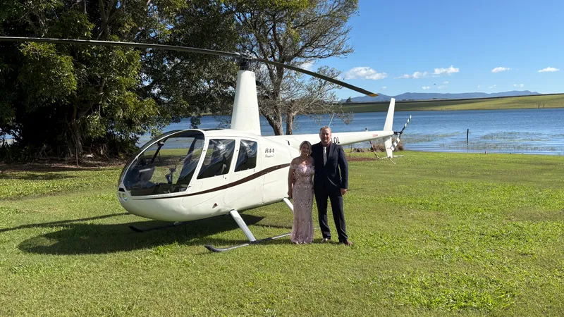 A wedding couple in front of a helicopter on the Tablelands.
